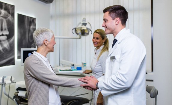 a patient shaking hands with her implant dentist in Rockwall