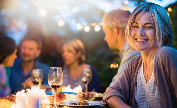 Woman smiling at dinner party with dental bridge in Rockwall