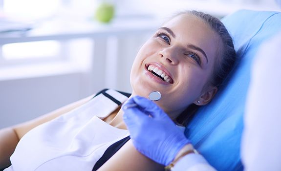 Woman smiling while visiting an emergency dentist in Rockwall