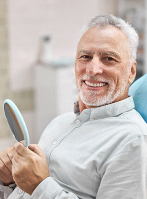 Man in dental chair smiling after full mouth reconstruction in Rockwall, TX