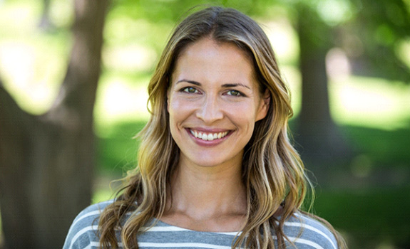 Woman smiling outside after full mouth reconstruction in Rockwall, TX