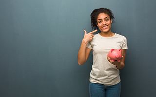 woman holding a piggy bank and pointing to her smile