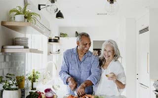 Older couple with dental implants in Rockwall preparing a meal