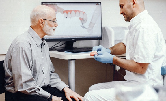 Man learning how implant dentures work in Rockwall