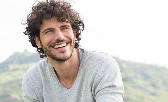 Man in grey shirt outside and smiling