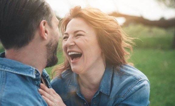 Man and woman laughing together after dental implant tooth replacement