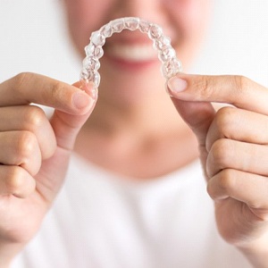 Woman in background holding up Invisalign in Rockwall