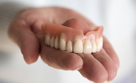 Hand holding full denture