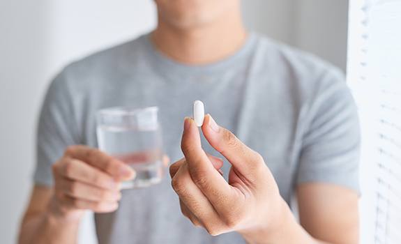 Patient holding a glass of water and oral conscious dental sedation pill