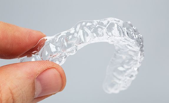 Hand holding Invisalign tray