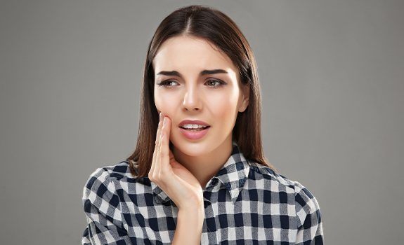 Woman in need of root canal holding cheek