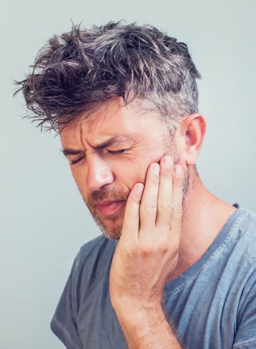 a man holding his cheek due to failed dental implant