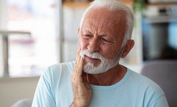 a man holding his cheek due to tooth pain