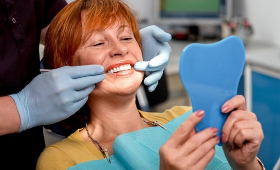 a patient smiling and checking her preserved dental implants