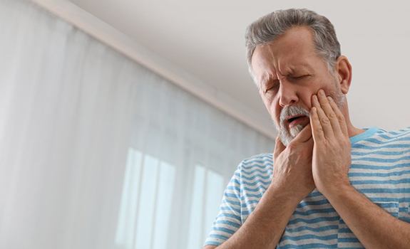 a man holding his jaw due to failed dental implant