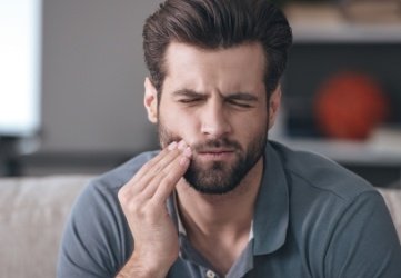 Man in need of emergency dentistry holding jaw