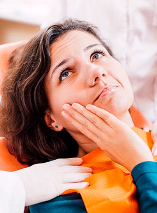 Woman with toothache visiting dentist for tooth extraction in Rockwall