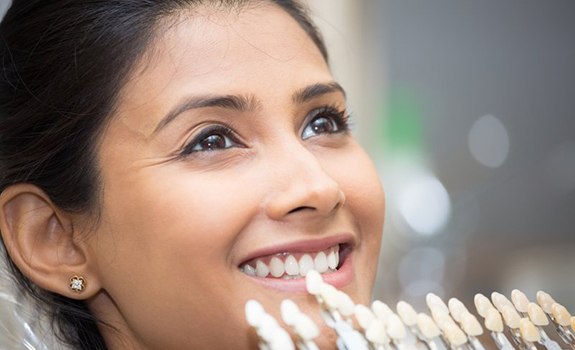 Woman smiles as cosmetic dentist places veneers