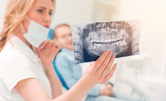 a dentist looking at an X-ray of wisdom teeth