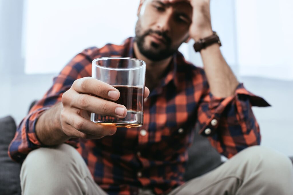 Man in plaid shirt holding glass of alcohol