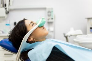 Woman receiving nitrous oxide through nasal mask in dentist’s chair.